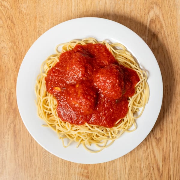 Spaghetti with meatballs and rich red marinara sauce on a white plate.