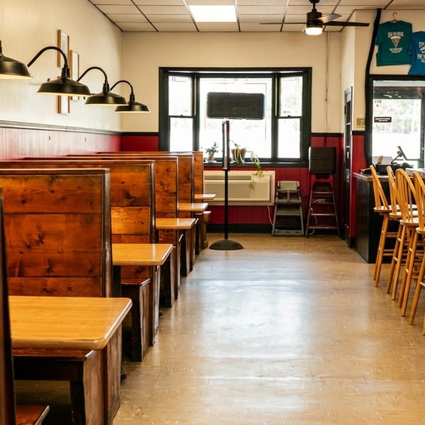 Interior of a restaurant with wooden booths, bar seating, and red wainscoting.