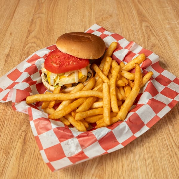 Cheeseburger with tomato, lettuce, and fries in a red and white checkered paper basket.